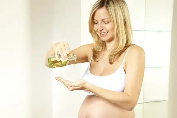 беременная женщина втирает в кожу кунжутное масло