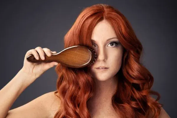 Рыжая девушка расчёсывает волосы