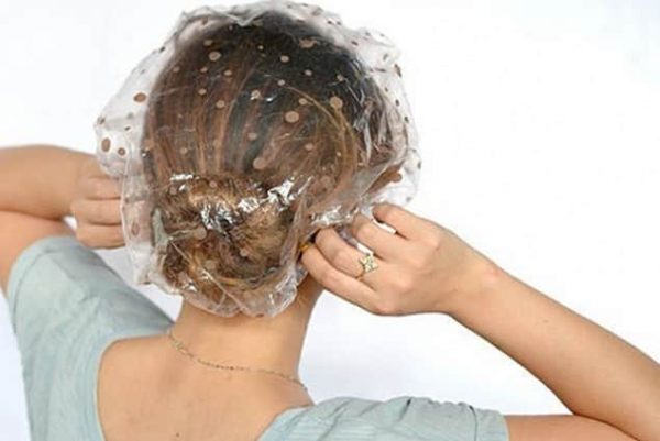 Девушка надевает полиэтиленовую шапочку на волосы