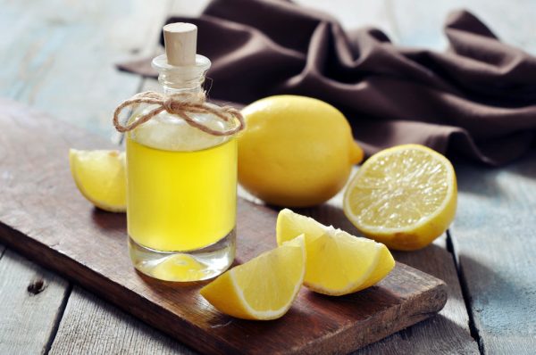 Лимоны и бутылка с лимонным соком на столе