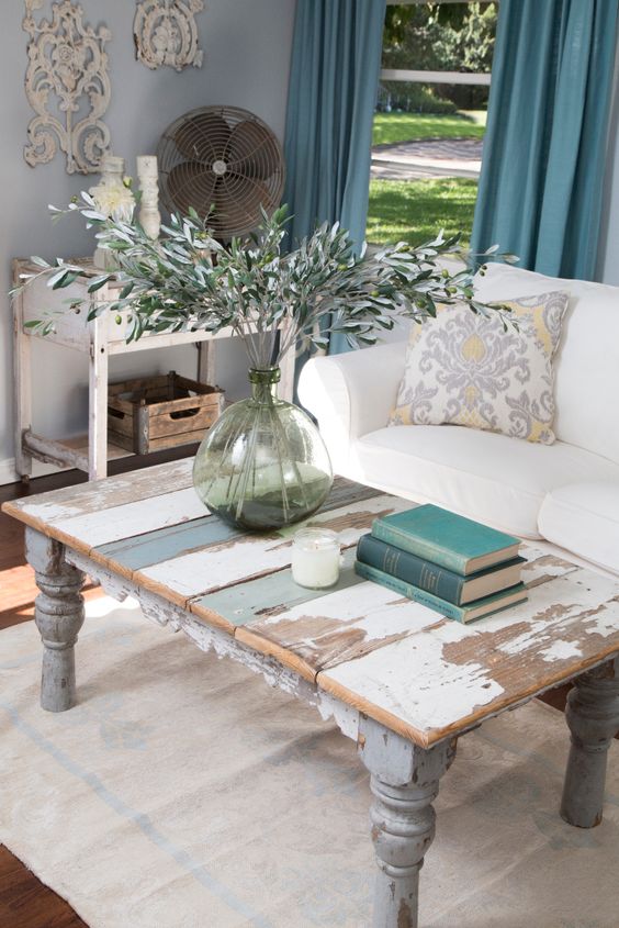 Fixer Upper Host Joanna Gaines staged the newly painted living room with bright and feminine, yet rustic furniture and accessories, making the room feel cozy. A coffee table made from reclaimed wood helps create a French country style, as seen on HGTV’s Fixer Upper. (detail)